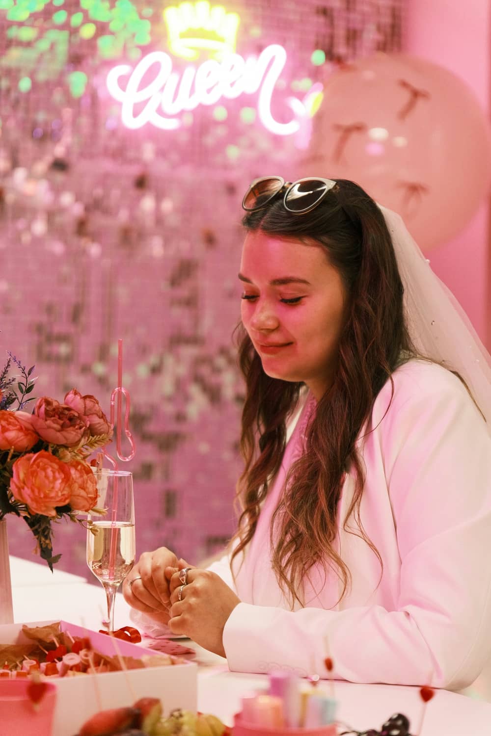 A bride in her veil laughing at a pink hen party